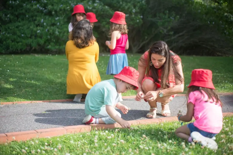 Caregiver sitting on the floor playing with toddlers and blocks